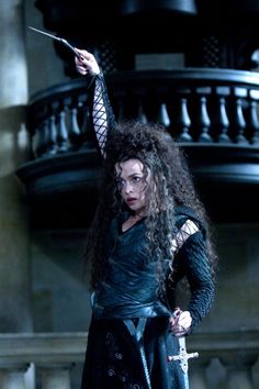 a woman with long curly hair standing in front of a staircase