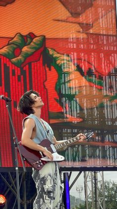 a man standing on top of a stage with a guitar in front of his face