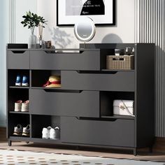 a black dresser with drawers and shoes on it in front of a wall mounted poster