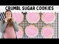 a woman standing in front of some cookies with pink icing on them and the words crumbl sugar cookies