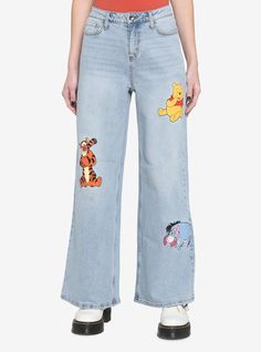 a woman wearing jeans with winnie the pooh patches on them