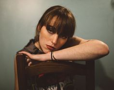 a woman sitting in a chair with her arm resting on the back of her head