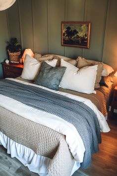 a bed with many pillows on top of it in a bedroom next to two lamps