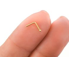 a tiny gold nose piercing on the tip of someone's finger