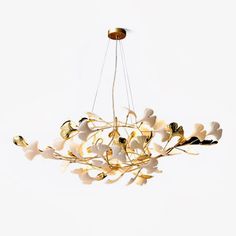 a chandelier with white flowers hanging from it's center and gold accents