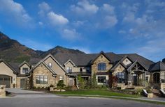 a large house with lots of windows in front of a mountain range and blue sky