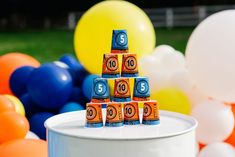 there is a cake made to look like a tower with numbers on it and balloons in the background