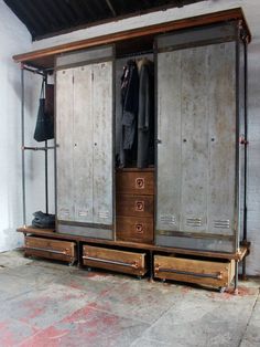 an industrial style closet with two drawers and three coats hanging on the doors, in a garage