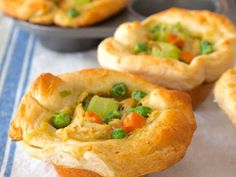 several small pies with peas and carrots in them on a blue and white table cloth