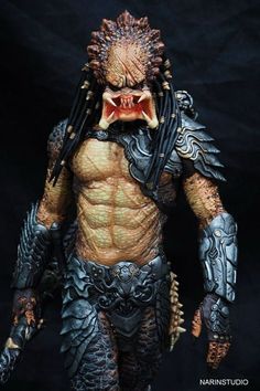 the predator action figure is shown in full armor, with his mouth open and fangs out