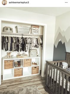 a baby's room with mountains painted on the wall and shelves filled with clothes