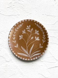 a brown and white plate sitting on top of a wall