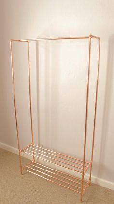 a gold metal rack with two shelves on the bottom and one shelf below it, against a white wall