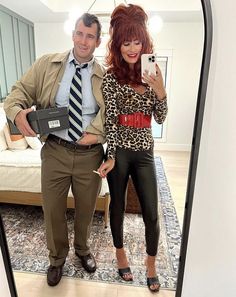 a man standing next to a woman in front of a mirror holding a cell phone