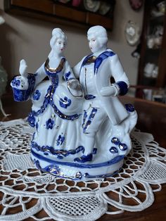 two figurines sitting on top of a doily