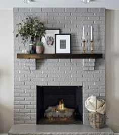 a white brick fireplace with candles and pictures on the mantle