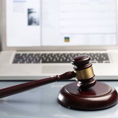 a wooden judge's gavel sitting in front of a laptop