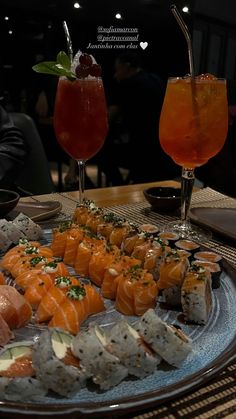 sushi platter with two drinks on the side and another plate full of sushi