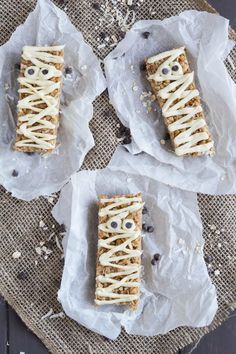 three pieces of food with white icing on them sitting on top of some paper