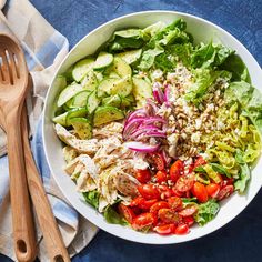 a salad with chicken, tomatoes, cucumbers and onions in a white bowl