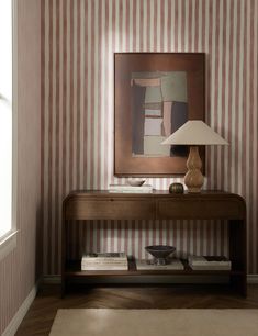 a room with striped wallpaper and a painting on the wall next to a table