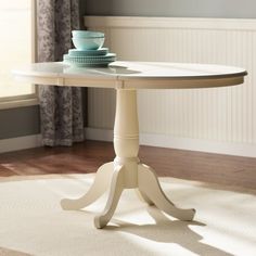 a white table with two plates on it in front of a window and curtained wall