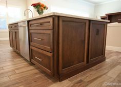 an island in the middle of a kitchen with wooden floors and cabinets on both sides