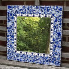 a blue and white mirror sitting on top of a wooden bench