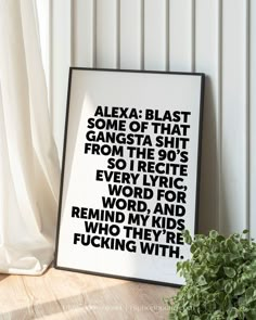 a black and white poster sitting on top of a wooden table next to a potted plant