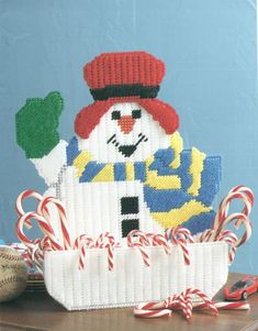 a knitted snowman sitting on top of a table next to candy canes