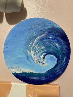 a painting of a wave in the ocean on a wall next to a toilet paper roll