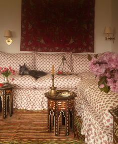 a living room filled with furniture and flowers on top of a carpeted floor next to a wall