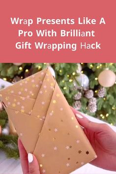 someone is holding an envelope with gold stars on it and the text wrap presents like a pro with brilliant gift wrapping hack