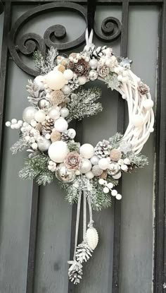 a wreath hanging on the front door of a building with pine cones and other decorations