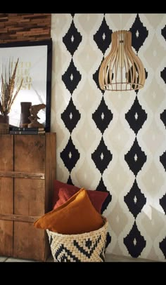 a black and white wallpaper with an orange pillow in the corner next to a wooden chest