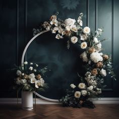 white flowers are arranged around a circular wreath on the floor in front of a dark green wall