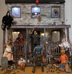 a group of halloween figurines in front of a house with decorations on the porch