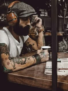 a man with tattoos sitting at a table