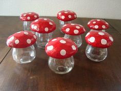 a group of red and white mushrooms sitting on top of a wooden table next to each other