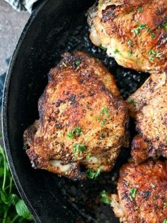 some meat is cooking in a skillet on the stove with parsley around it