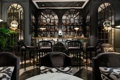 the bar is decorated in black and gold with lots of chairs around it, along with an area rug on the floor