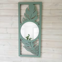 a mirror that is on the wall with a plant in it's reflection,