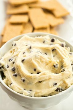 a white bowl filled with cream cheese and chocolate chip crackers next to some crackers