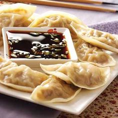 dumplings with dipping sauce on a white plate