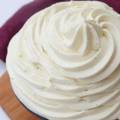 a cupcake with white frosting sitting on top of a table