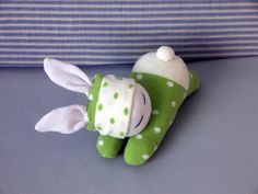 a green and white stuffed animal laying on top of a bed