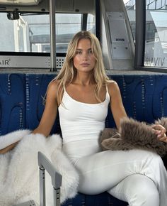 a woman is sitting on a bus with her legs crossed and holding a stuffed animal