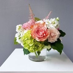 a vase filled with flowers sitting on top of a white table next to a gray wall