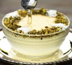 a spoon in a bowl filled with food on top of a metal saucer and silver plate