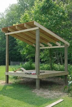 a wooden bed sitting in the middle of a lush green field